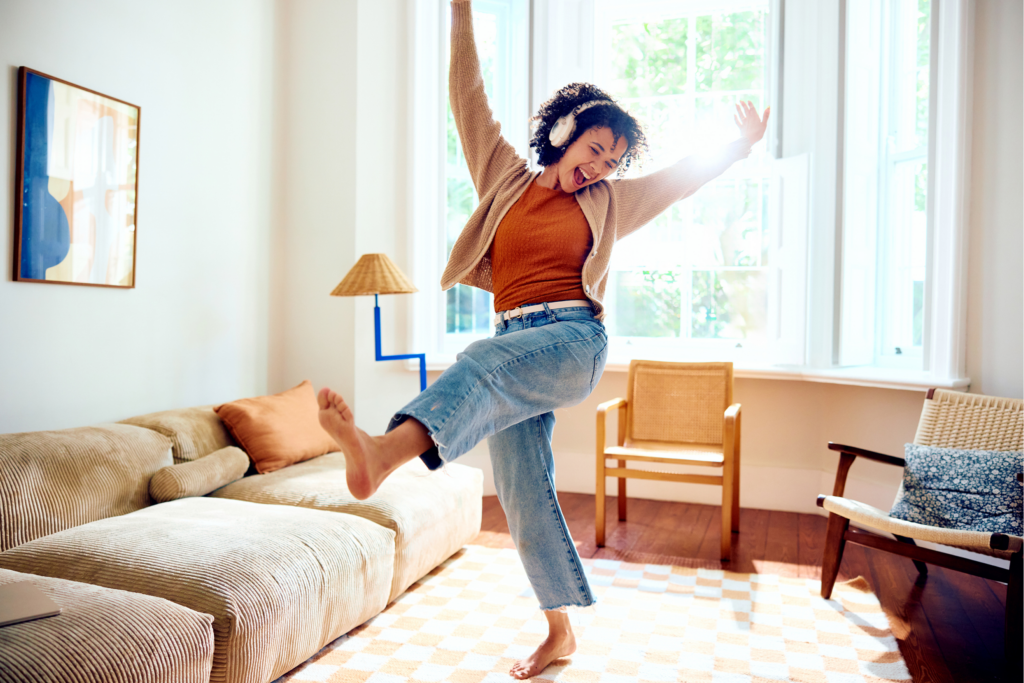 woman dancing in the living room with her headphones one