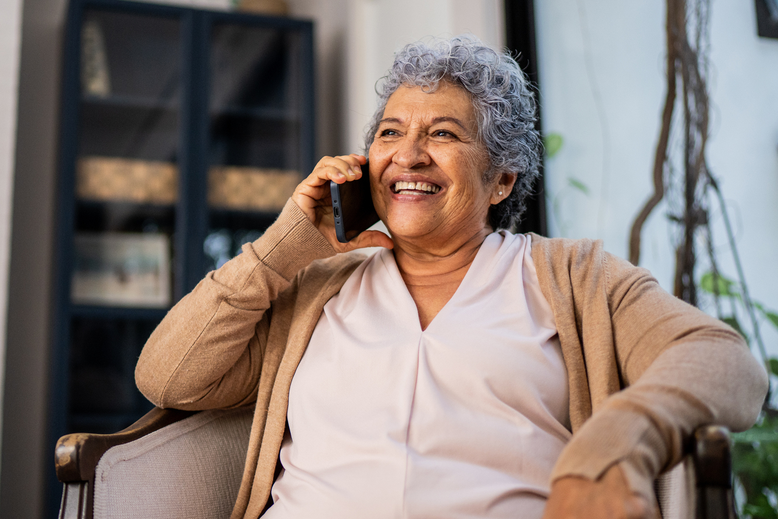 woman with grey hair talking and smiling on the phone